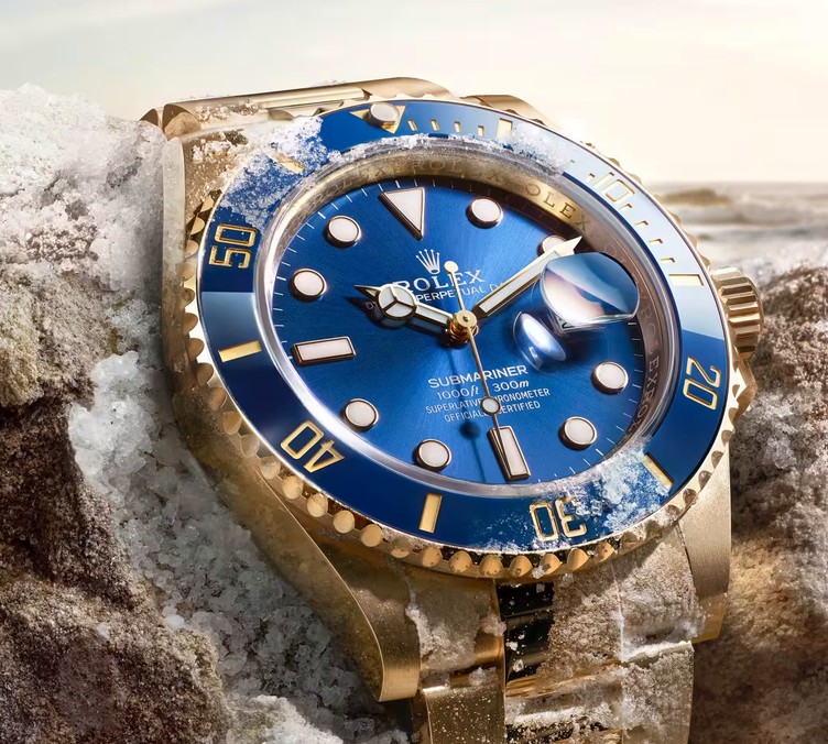 Gold Rolex Submariner with blue dial resting on crushed ice